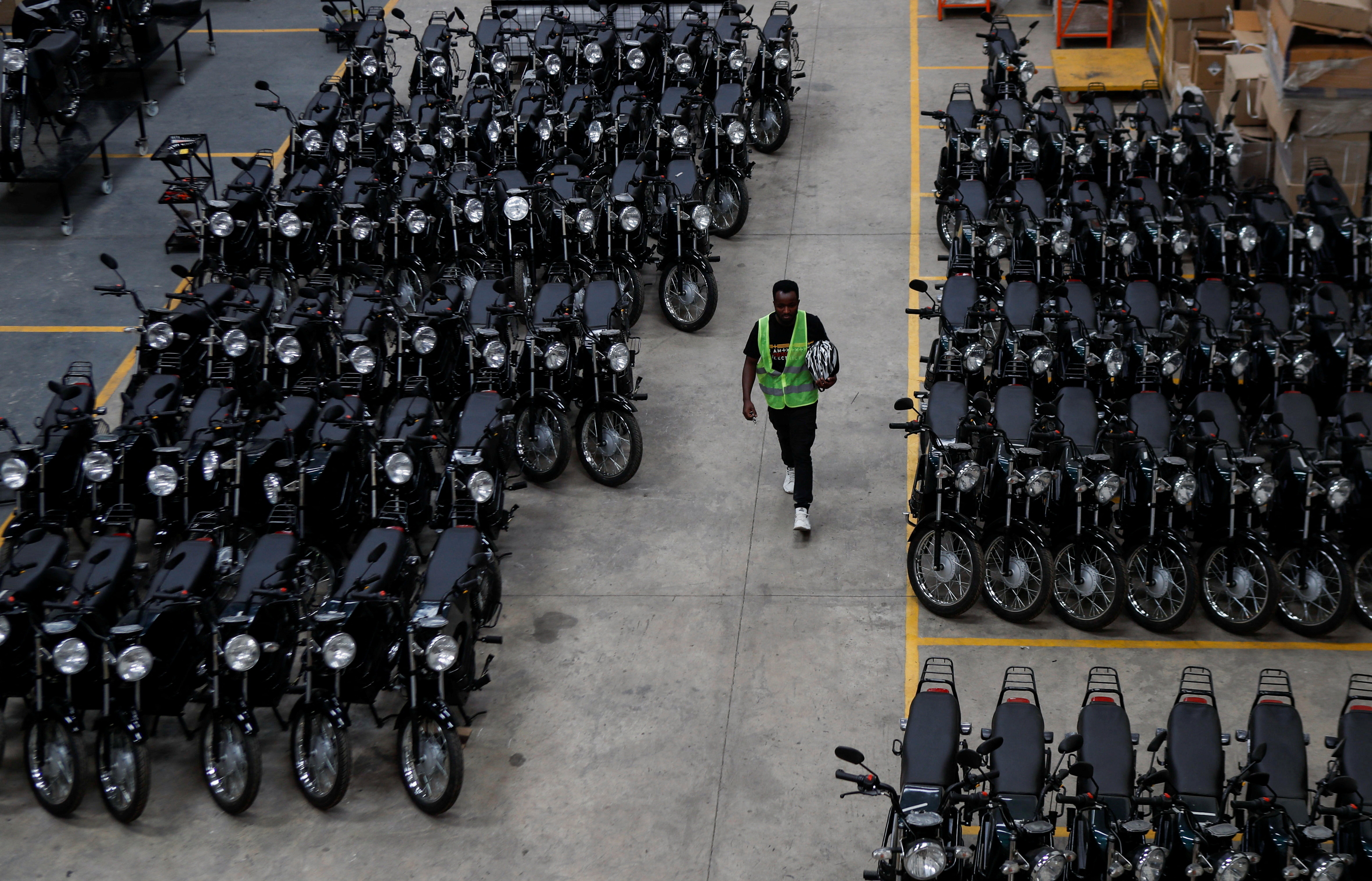 A worker walks next to assembled electric motorcycles at ARC Ride's warehouse in Industrial Area, Nairobi, Kenya November 2, 2022. REUTERS/Monicah Mwangi
